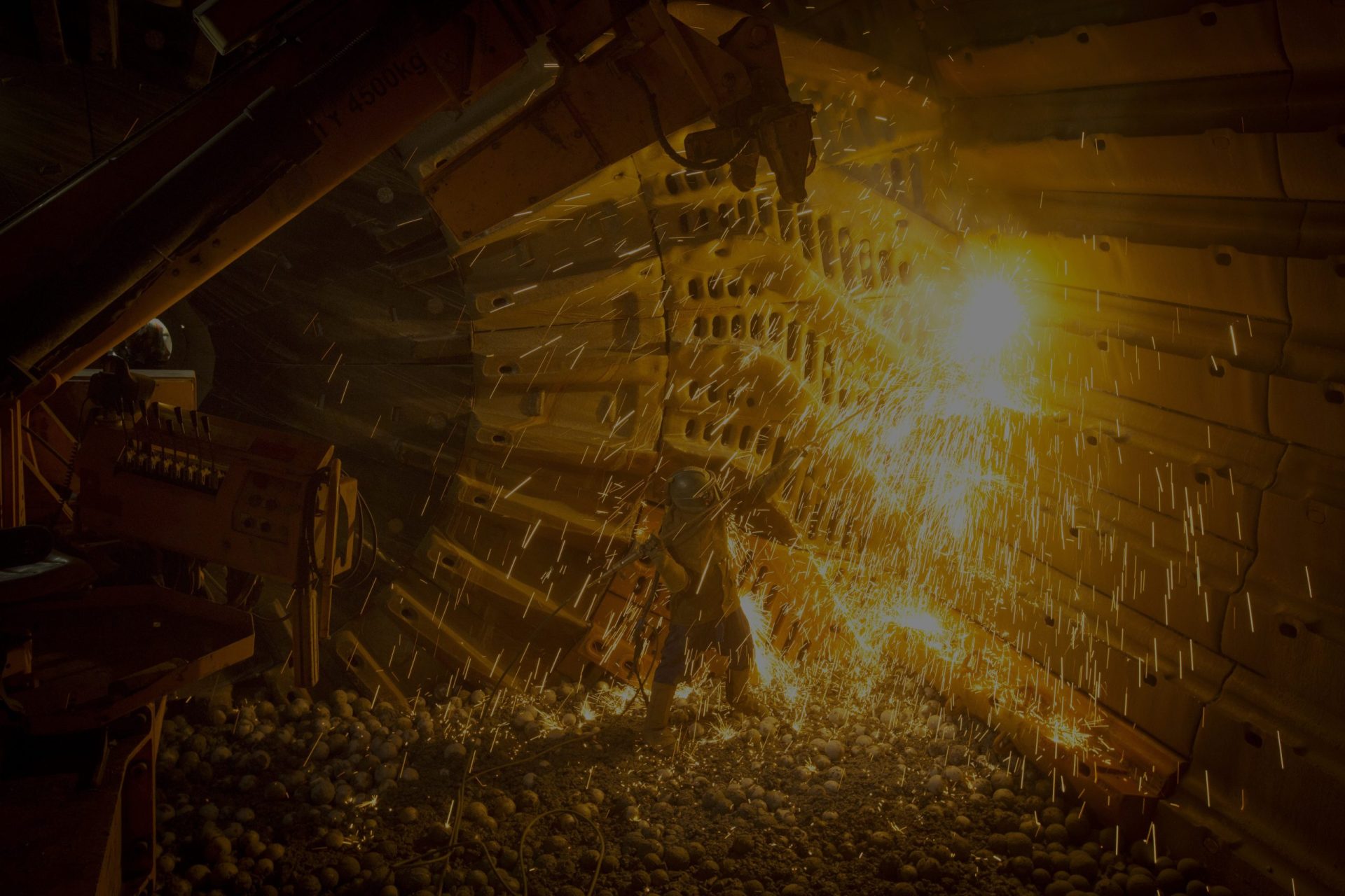 A Kaltech reliner working inside a grinding mill amid a shower of sparks
